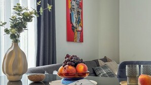 Ett modernt vardagsrum med en soffa, ett soffbord med en fruktskål, en vas och en tavla på väggen.