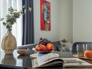 A modern living room with a sofa, a coffee table with a fruit bowl, a vase, and a painting on the wall. - Apartment 1+1 Qoople Saga 3 on Cleopatra Beach (Alanya)