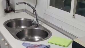 A kitchen with two stainless steel sinks, a microwave, and a window with a view of a plant. - Malaga. Apartamento a un minuto de la playa (Rincón de la Victoria)