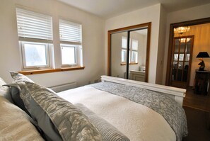 A bedroom with a large bed, a mirror, and a window with blinds. - Seaside Nook- stylish stay by the sea (Anstruther)