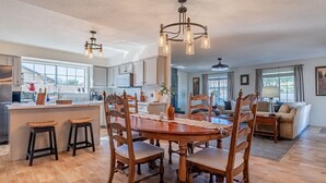 A spacious kitchen with a central island, wooden chairs, and a chandelier. - Family Friendly Resort | Pool | Yard | Games (Yuma)