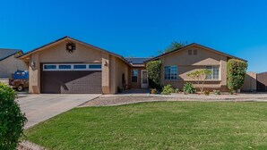 A two-story house with a garage, a driveway, and a well-maintained lawn. - Family Friendly Resort | Pool | Yard | Games (Yuma)