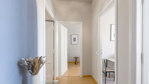 Un pasillo con piso de madera, paredes blancas y una puerta blanca al final.