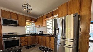 Una cocina moderna con armarios de madera, electrodomésticos de acero inoxidable y piso con diseño en espiga.