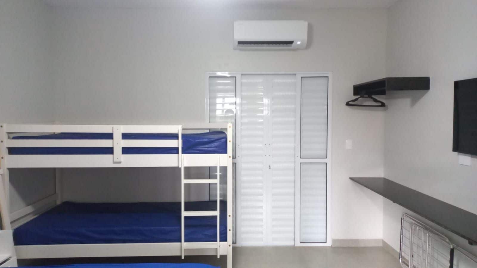 Un dormitorio con literas, un armario, un televisor y un radiador.