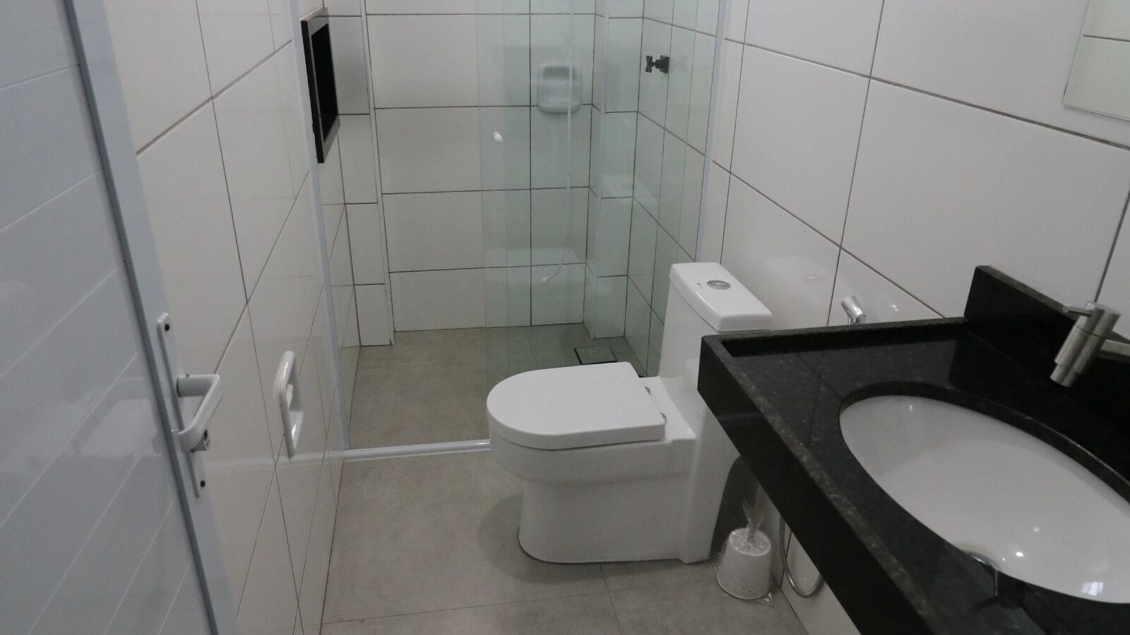 A modern bathroom with a toilet, a glass shower enclosure, and a black sink.