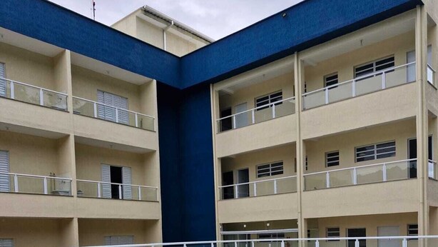 Une piscine avec une fontaine, entourée d’un immeuble à plusieurs étages doté de balcons et d’une terrasse carrelée.