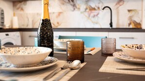 A dining table set with a bottle of champagne, bowls, and glasses. - Easylife - A 2 passi dal mare Sant'Isidoro (Sant'Isidoro)