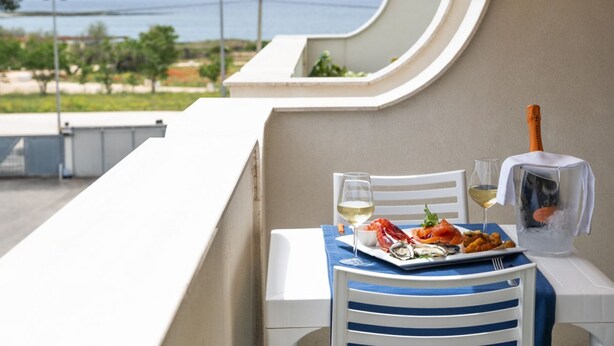 A balcony with a table set for a meal, overlooking a coastal view. - Easylife - A 2 passi dal mare Sant'Isidoro (Sant'Isidoro)