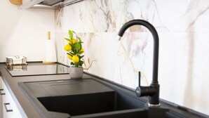A kitchen with a black sink, a marble backsplash, and a potted plant with yellow flowers. - Easylife - A 2 passi dal mare Sant'Isidoro (Sant'Isidoro)