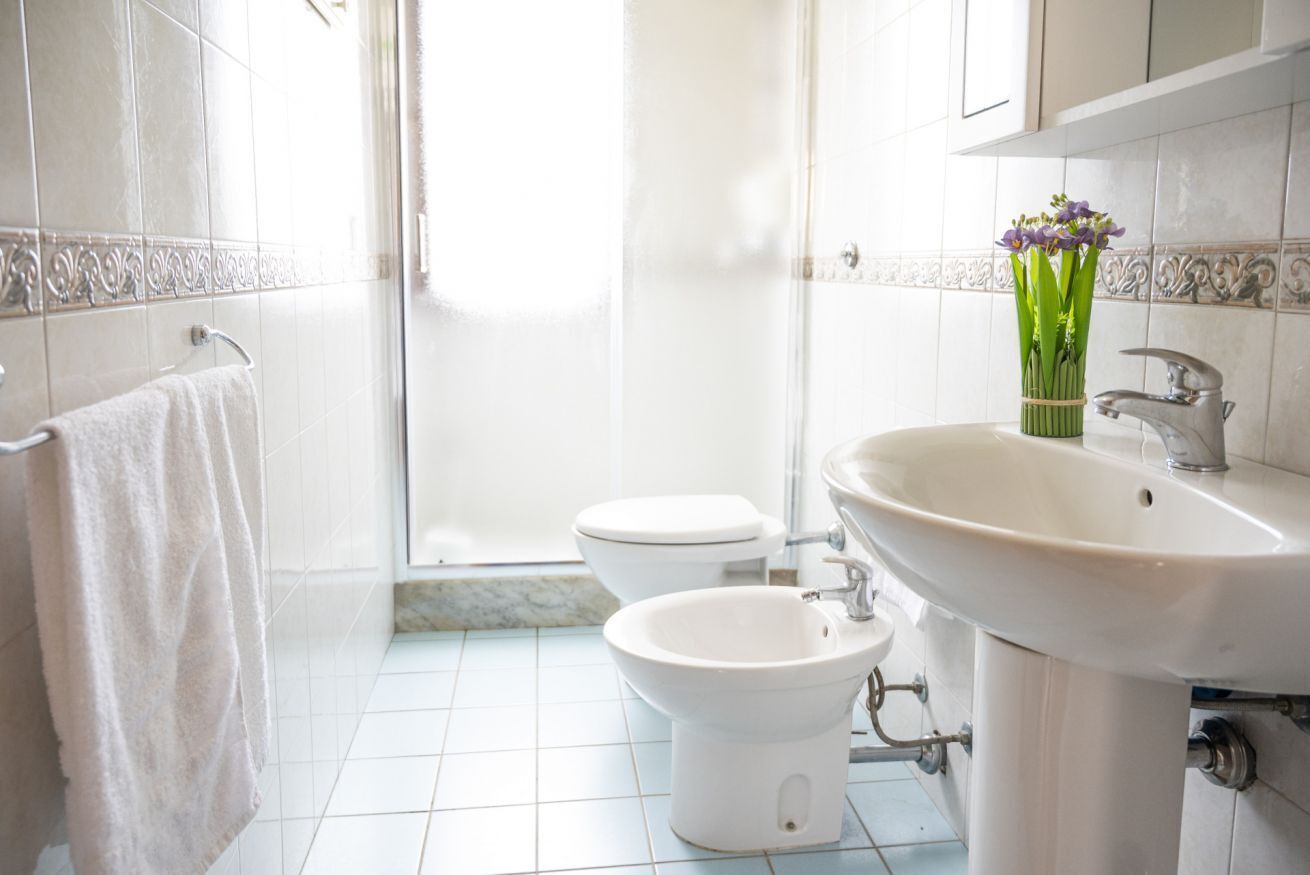A bathroom with a toilet, bidet, sink, and a towel hanging on a rack.