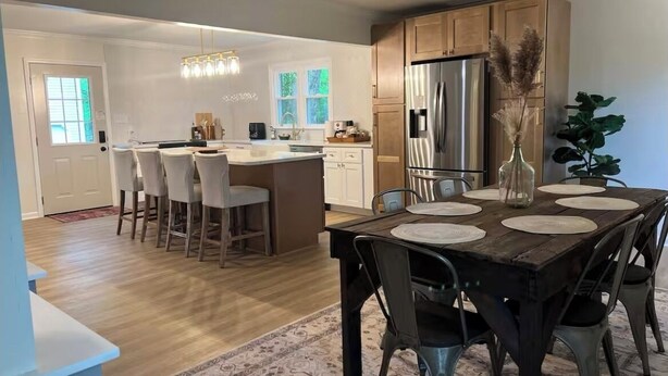 Una cocina moderna con una isla central, electrodomésticos de acero inoxidable y un comedor con mesa y sillas de madera.