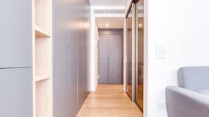 Un couloir avec un plancher en bois, des murs gris et un canapé gris.
