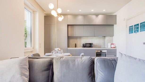 A modern kitchen with grey cabinets, a dining area with a table set for two, and a built-in oven. - Easylife - Style and balcony near the Duomo (Milano)