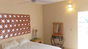 A bedroom with a bed, a ceiling fan, a decorative wall panel, a mirror, and a nightstand. - Rustic private 2BR/1.5ba house with yard in Bucerías Centro near Puerto Vallarta (Bucerías)