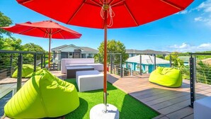 Een terras met rode parasols, groene relaxstoelen en witte banken.
