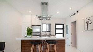 Een moderne keuken met een centraal eiland, roestvrijstalen apparatuur en een glazen afzuigkap.