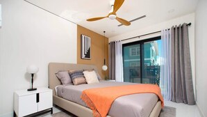 Een moderne slaapkamer met een bed, nachtkastje, plafondventilator en uitzicht door een groot raam.