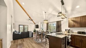 Een moderne keuken met een centraal eiland, houten keukenkastjes en een eethoek met uitzicht op de omgeving.