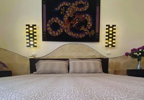 Ein Schlafzimmer mit einem Bett, zwei Wandleuchten und einem großen Wandbild darüber.