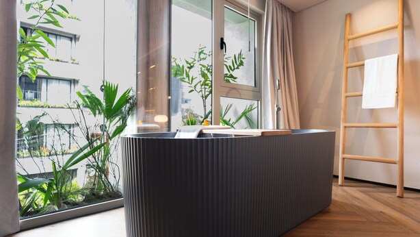 A modern room with a large window, a wooden ladder, and a grey textured bench. - BoH Collection (Medellín)