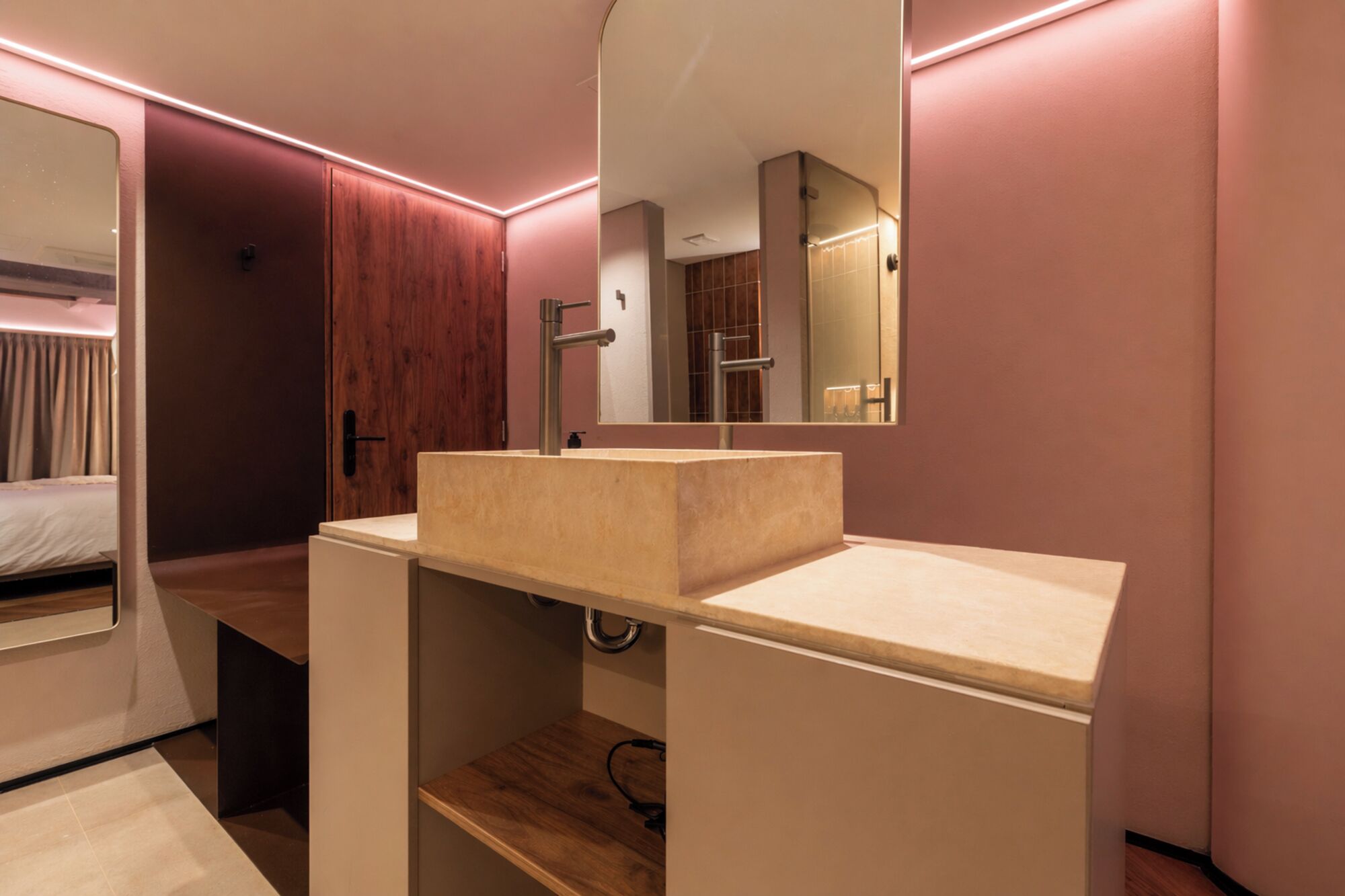 A modern bathroom with a wooden vanity, a large mirror, and a shower area.