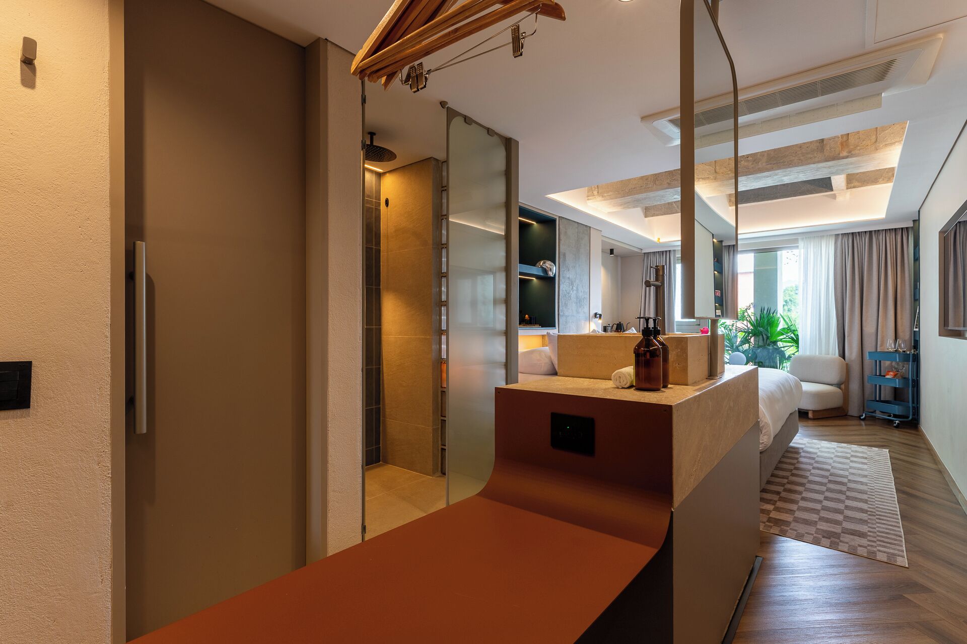 Habitación de hotel moderna con un espejo grande, techo de madera, ducha integrada y una zona de estar con vistas.