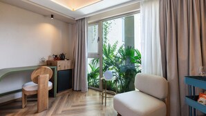 A modern hotel room with a wooden desk, a comfortable chair, a sofa, and a large window with curtains. - BoH Collection (Medellín)
