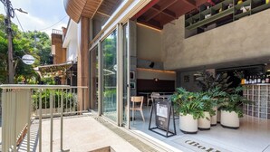 A modern building with a glass entrance, outdoor seating, and a bar area with potted plants. - BoH Collection (Medellín)