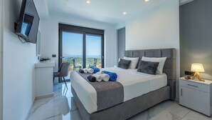 Ein modernes Schlafzimmer mit einem großen Bett, einem an der Wand befestigten Fernseher und einem Balkon mit Blick.