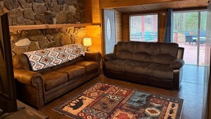 A cozy room with a stone wall, a brown leather sofa, a patterned rug, and a wooden ceiling. - Dogwood Legend 3 Mins From DTWN Jasper (Jasper)