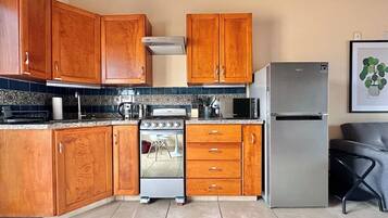 Una cocina con armarios de madera, un refrigerador de acero inoxidable, una estufa y un microondas.
