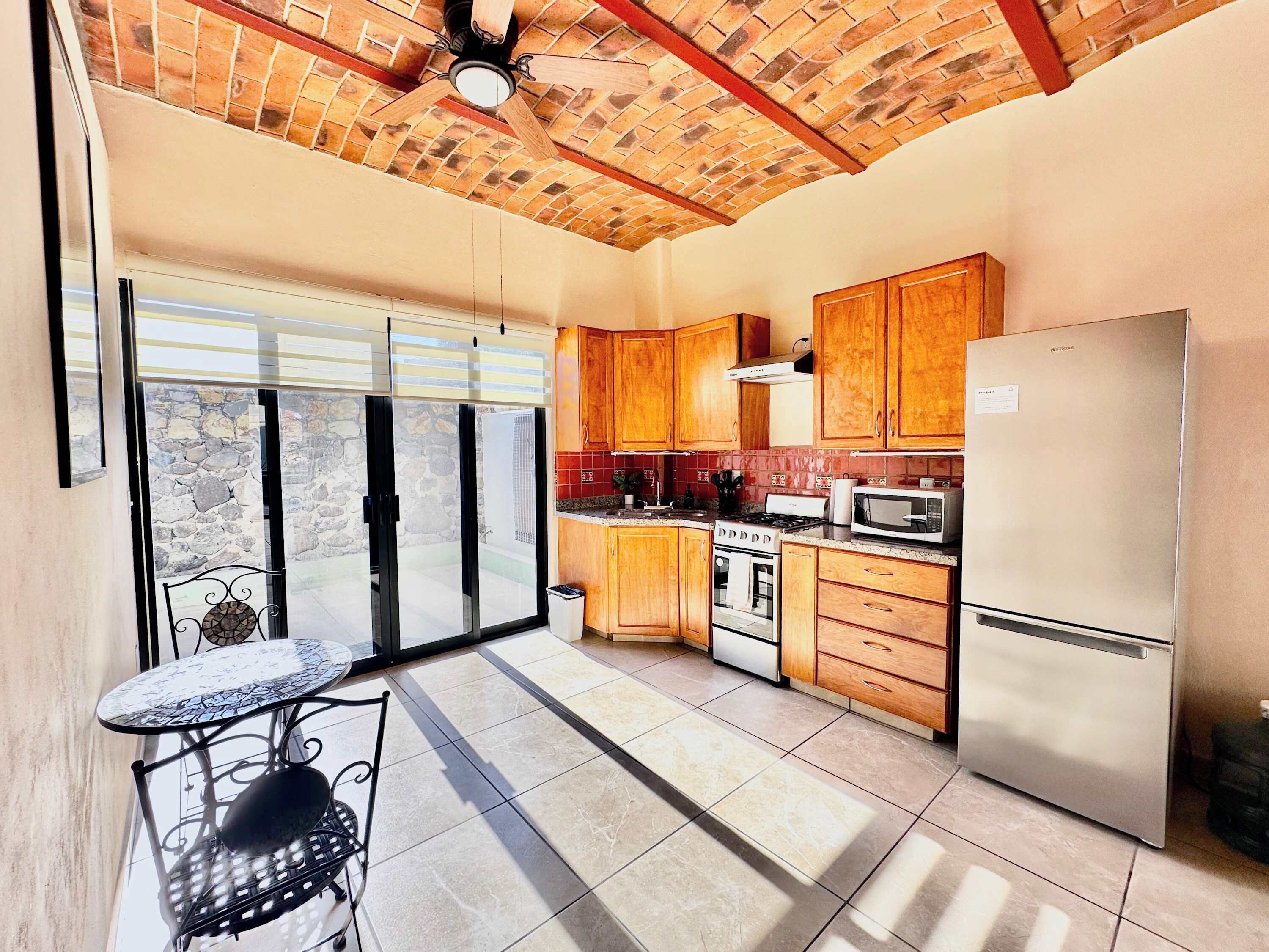 A kitchen with wooden cabinets, a stainless steel refrigerator, a stove, and a microwave.