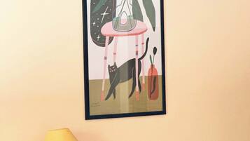 A room with a bed, a bedside table with a lamp, and a framed abstract artwork on the wall.