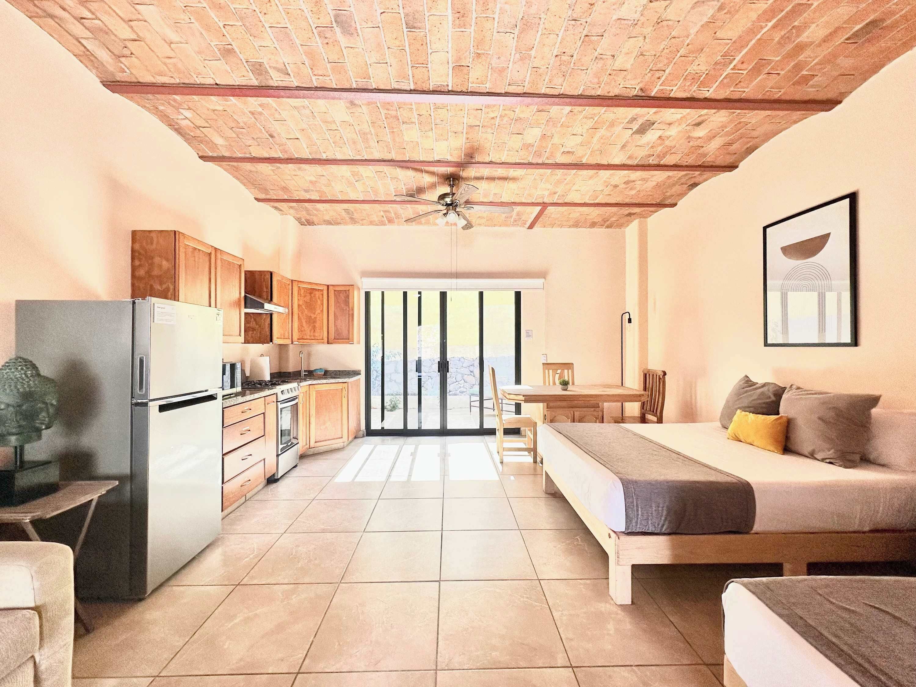 A spacious room with a kitchen, a dining area, and a bed.