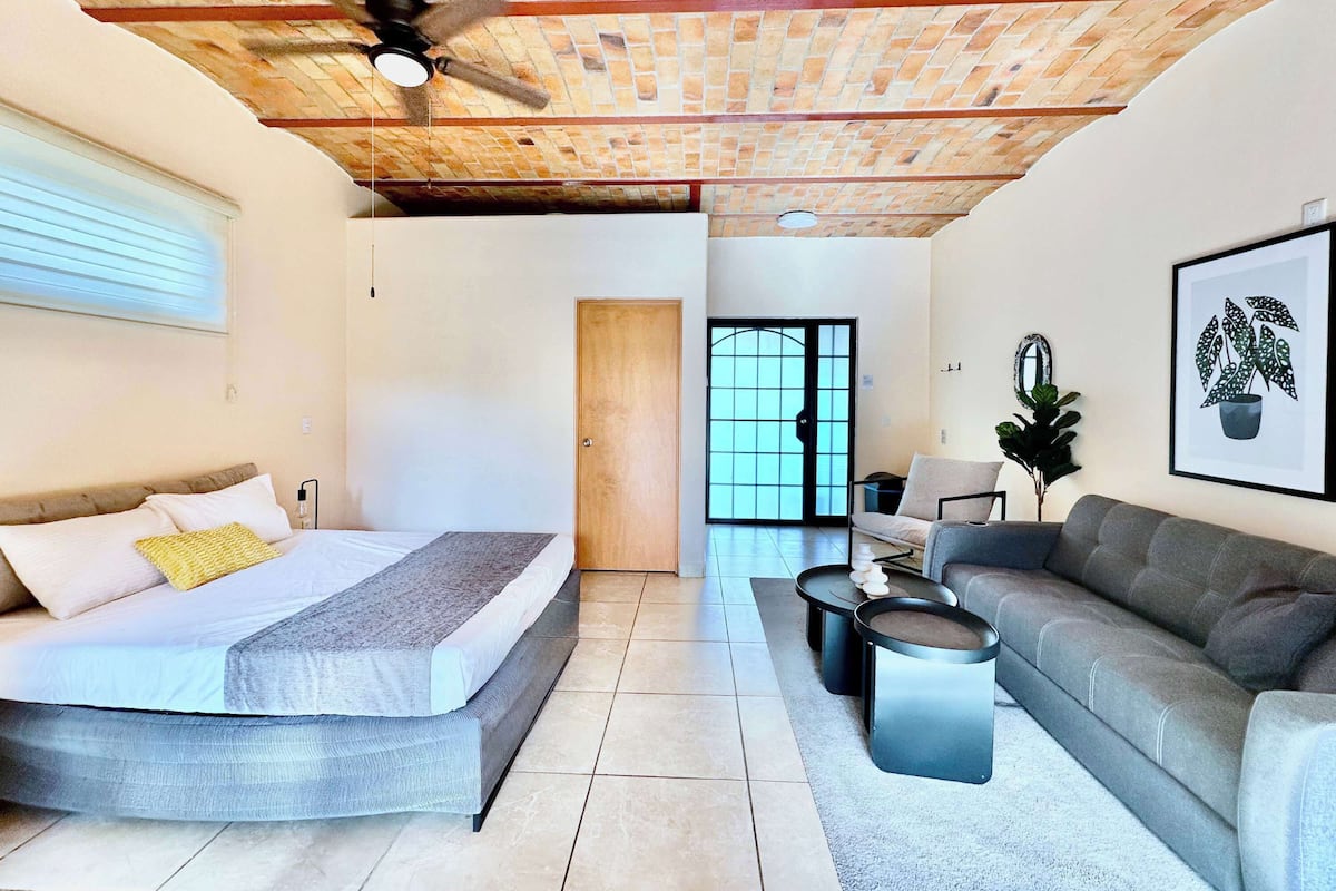 Une chambre moderne équipée d’un lit, d’un canapé et d’un ventilateur de plafond.