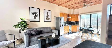A modern living room with a grey sofa, two black coffee tables, and a large window.