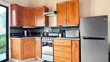 A kitchen with wooden cabinets, a stainless steel refrigerator, a stove, and a microwave.