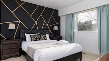 Ein Hotelzimmer mit einem Bett, Nachttischen, einem Fenster mit Vorhängen und einem geometrischen Wanddesign.