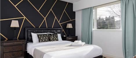 A hotel room with a bed, nightstands, a window with curtains, and a geometric wall design.