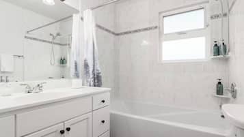 Un baño con tocador blanco, bañera, inodoro y ducha.