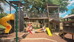 Un parque infantil con tobogán, estructuras para escalar y una zona de estar cubierta.