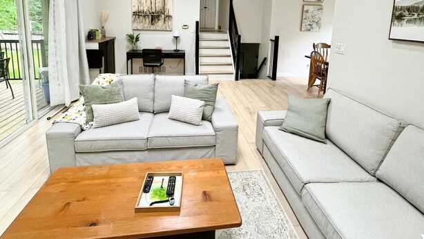 Ein modernes Wohnzimmer mit einer Couch, einem Couchtisch und einer Treppe, die eine weitere Ebene hinaufführt.
