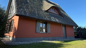 Uma casa com telhado de palha e uma pequena janela com persianas.