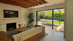 Een moderne woonkamer met een open haard, een groot raam en uitzicht op de natuur.
