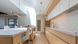 Een moderne keuken met een centraal eiland, houten kastjes en uitzicht naar buiten.