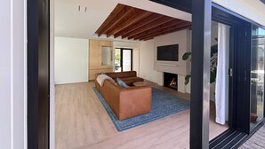 Een moderne woonkamer met een bruine bank, een open haard en een aan de muur bevestigde televisie.