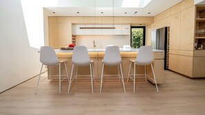 Een moderne keuken met een centraal eiland, barkrukken en een dakraam.