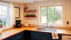 Cocina moderna con encimera de madera, pileta integrada y ventana con vista a árboles.