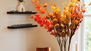 Una mesa de comedor con un florero de hojas otoñales, una vela y una lámpara de araña moderna.